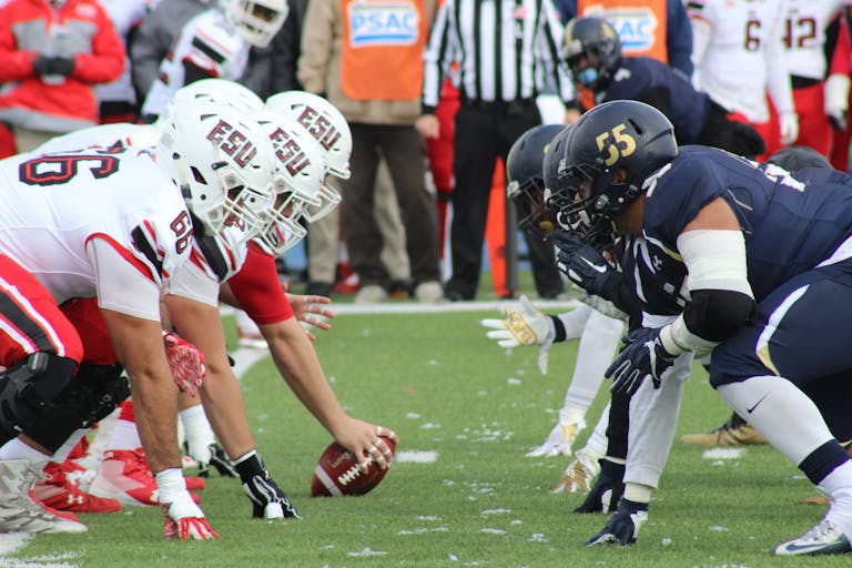 Rival football teams face off at the start of an action-packed game on the field.