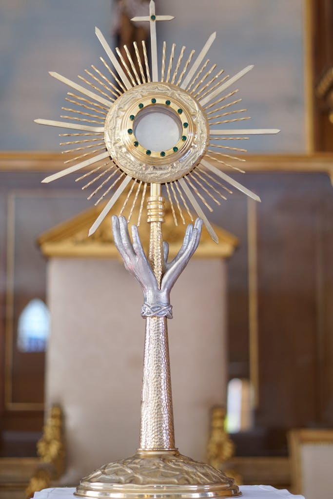 Ornate gold monstrance with a starburst design displayed in a church interior.